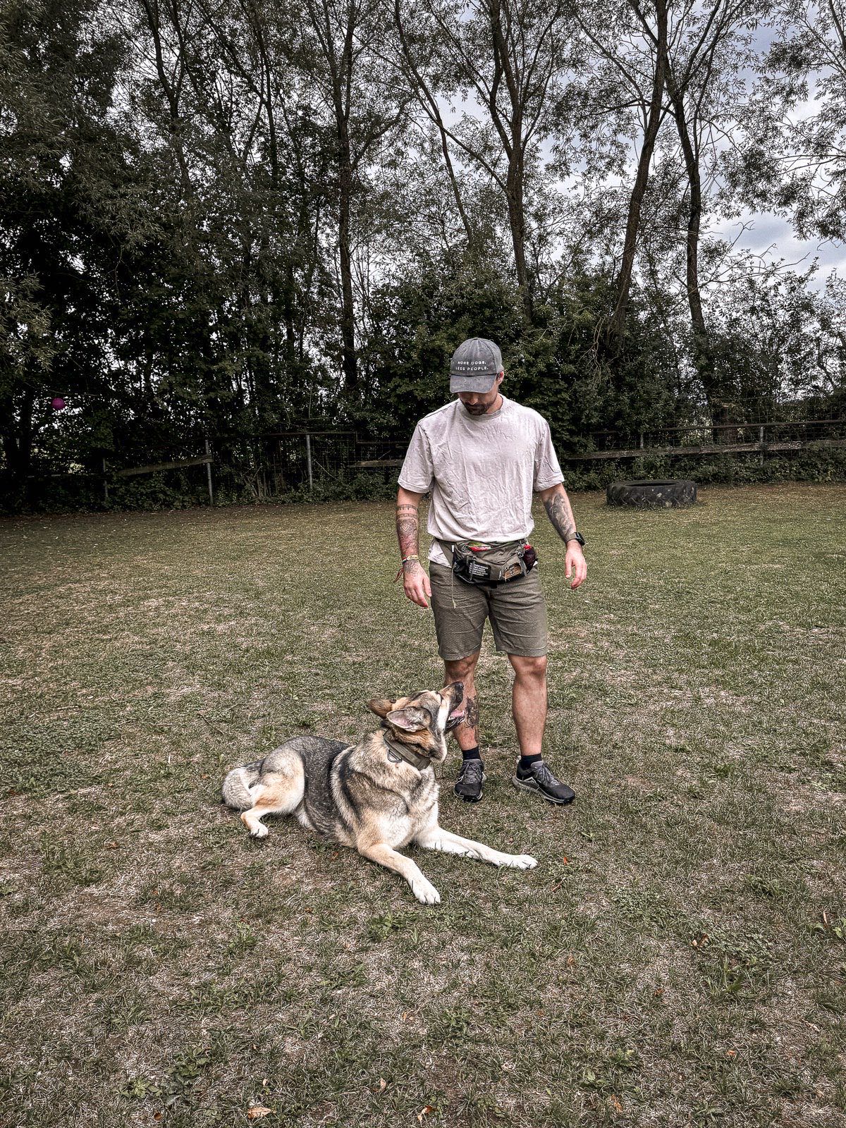 Milo liegt neben Michi auf einer Trainingswiese und schaut zu ihm.