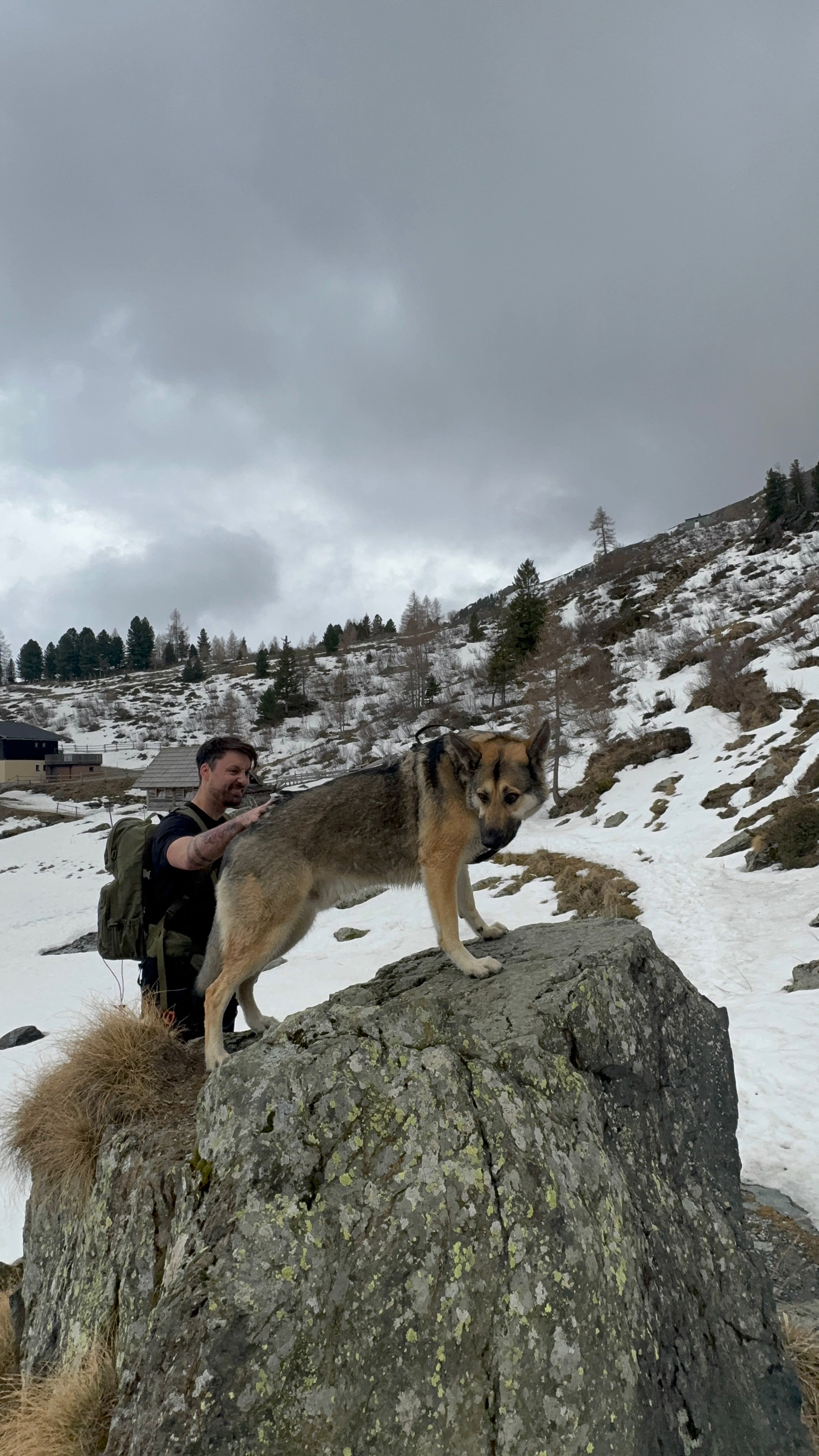 Michi steht neben Milo, der auf einem Felsen steht, und legt seine Hand an Milos Rücken.